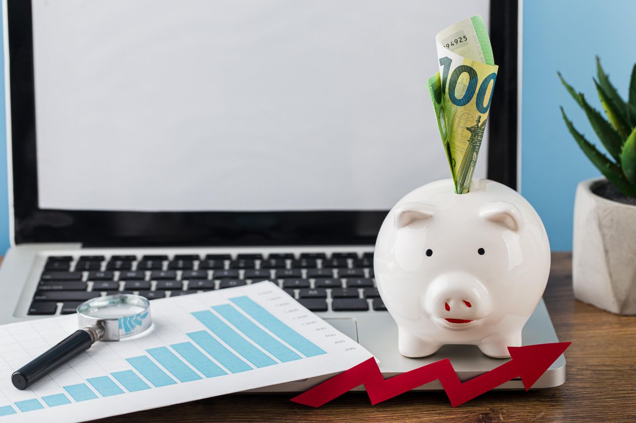 High angle of office items with piggy bank and laptop